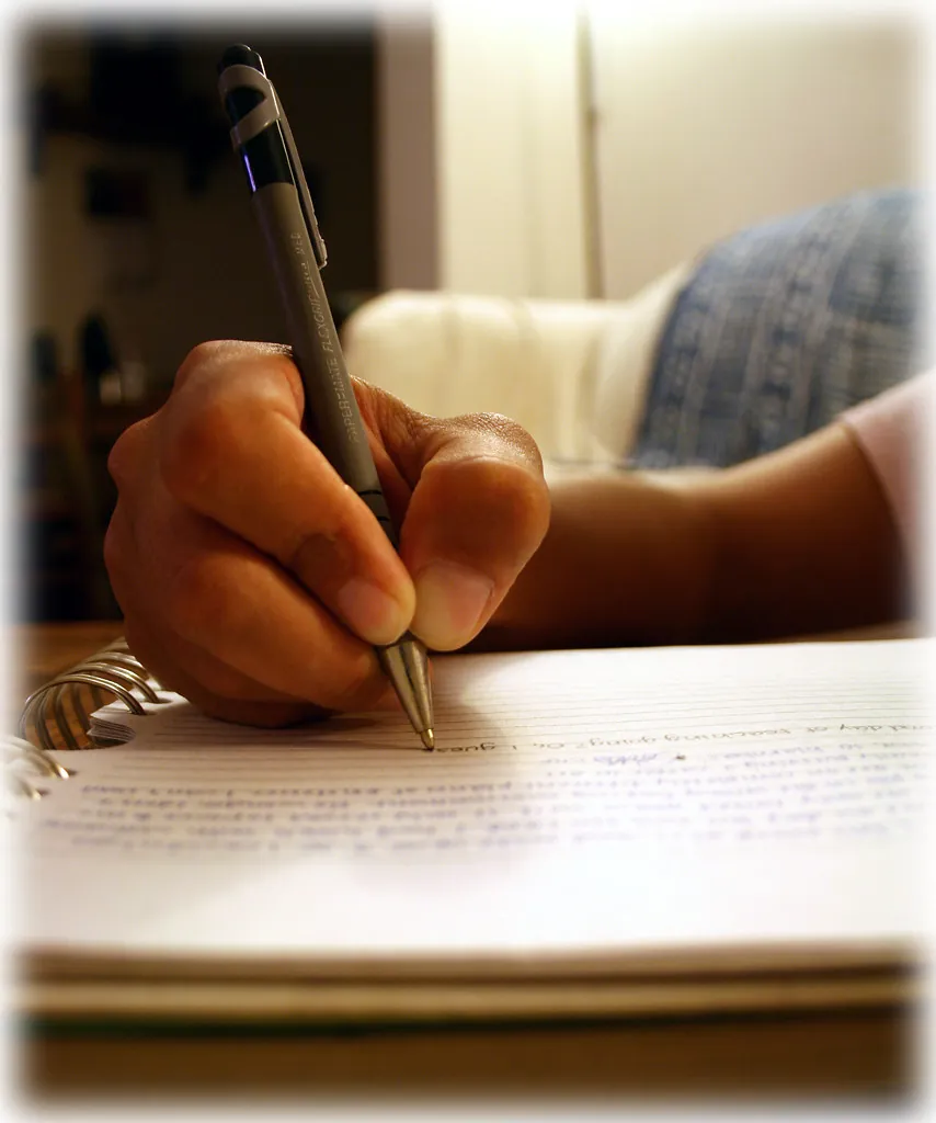 Mano escribiendo con pluma sobre un cuaderno